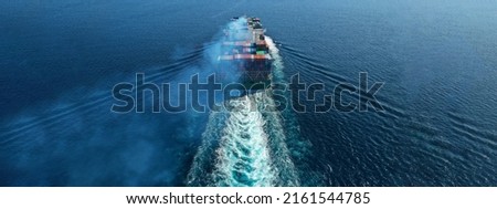 Aerial drone ultra wide photo over colourful truck size container tanker ship cruising deep blue sea near commercial port of Piraeus, Attica, Greece