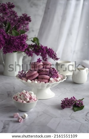 Vertical composition. A bouquet of lilacs and a vase with macaroons. A concept of holidays and wishes of good morning. 