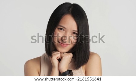 Beautiful Asian girl looking cute at camera isolated on white background. Pretty female smiling as hearing compliment from stranger