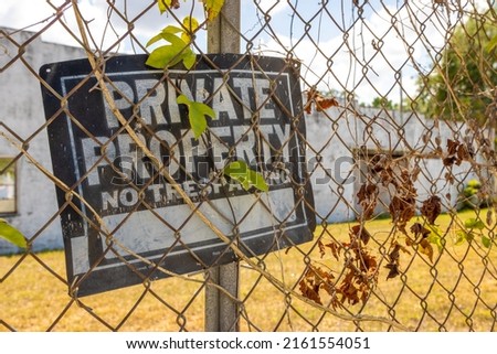 Private property sign on chain link fence next to abandoned building