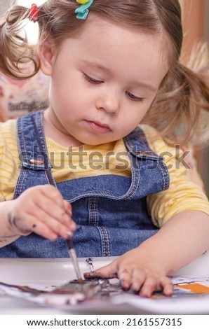 The concept of children's creativity. A one-and-a-half-year-old girl paints with paints