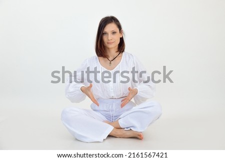 Attractive smiling brown-haired woman pose and sit in white studio, look camera. Imaginary place for text. Copy space