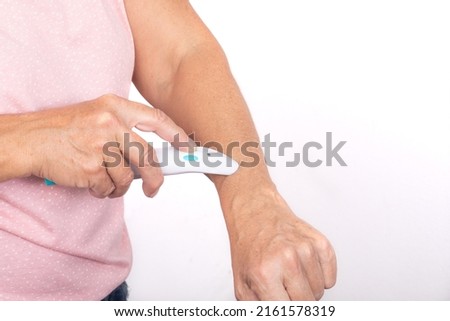 A woman treats a mosquito bite on her arm with an electric bite healer - isolated on white background. Royalty-Free Stock Photo #2161578319