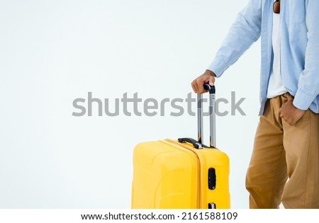 Ready to trip. Suitcase handle in young casual man's hand, blue jeans shirt and brown trousers isolated on white background with copy space. Summer vacation, holiday, tourist, journey concept.