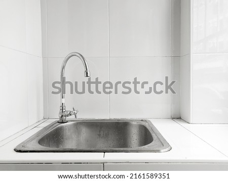 Stainless steel sink and faucet  on white tiles, modern room