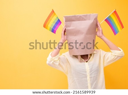 Pride month Cheering anonymous people girl with shopping bag head.holding in hands covering ,LGBT,LGBTQ flag having fun celebrating isolated over yellow background.Sexual equality,Gay flag,Lesbian. Royalty-Free Stock Photo #2161589939