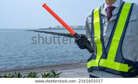 Red stick and security guard uniform.Industrial area of the sea.