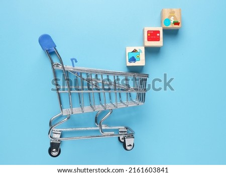 A picture of trolley with wooden block having e-wallet, debit credit card and online bank transfer. Online shopping payment method.