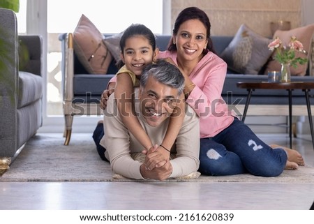 Portrait of cheerful parents with daughter lying down on carpet in the living room