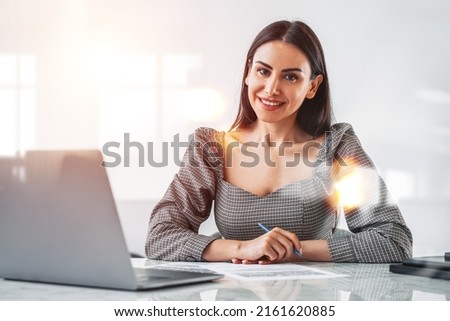 Office woman smiling, looking at the camera with contract on work desk. Smiling manager working in company room. Concept of secretary and reception