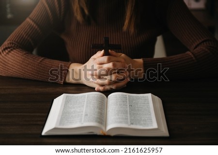 Woman sitting and studying the scriptures.The  wooden cross in the hands. Christian education concepts The Holy Scriptures open 
