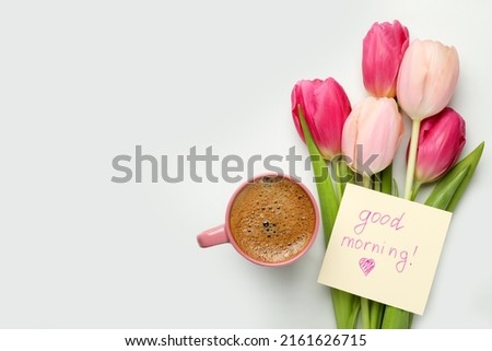 Cup of aromatic coffee, beautiful pink tulips and Good Morning note on white marble table, flat lay. Space for text