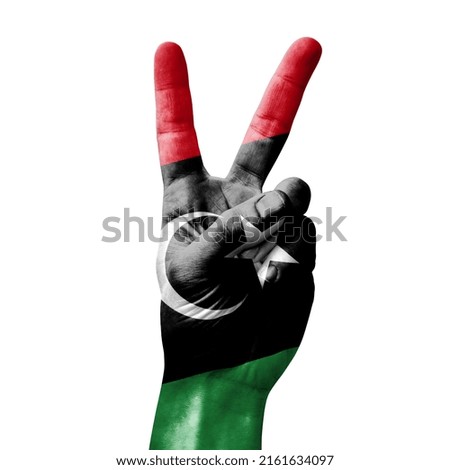 Hand making the V victory sign with flag of libya