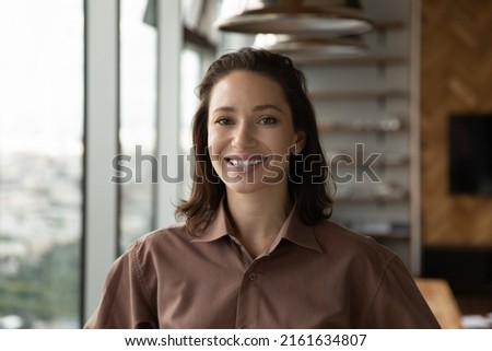 Headshot portrait of happy confident female leader, entrepreneur, self employed professional, office employee. Profile picture of young business woman looking at camera with toothy smile