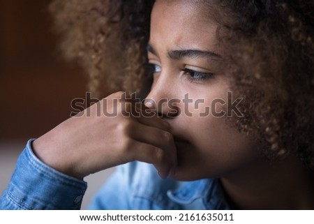 Sad concerned Black teenage girl thinking over problems, bad news, going through stress, anxiety, emotional trauma, abuse. Fae close up shot. Psychology, youth, adolescence concept Royalty-Free Stock Photo #2161635011