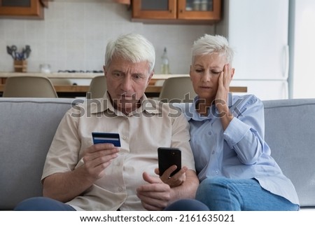 Shocked aged couple become victims of online fraud using credit card phone to pay for goods order service online on suspicious website. Frustrated older spouses overspending money at internet shopping Royalty-Free Stock Photo #2161635021