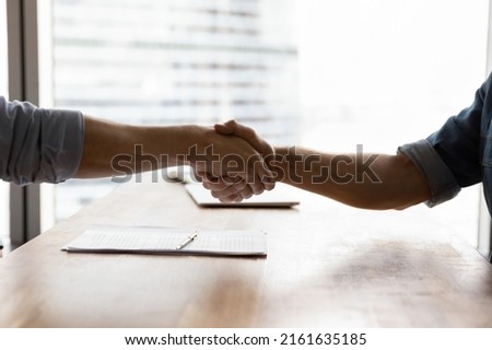 Two businessmen shaking hands over conference table in office. Business partners, client and lawyer giving handshakes after meeting. Employer hiring employee after job interview. Close up Royalty-Free Stock Photo #2161635185