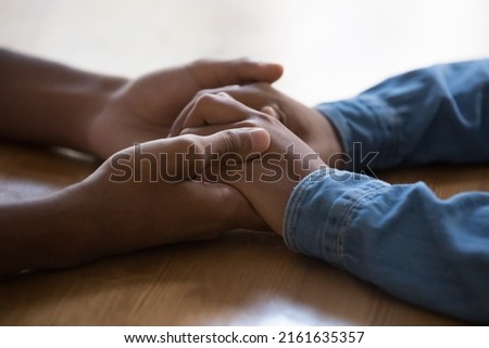 Young teen loving African couple holding arms on table surface. Guy touching hands of dark skinned Black girl, giving care, love, support, expressing tenderness, affection. Close up, cropped shot Royalty-Free Stock Photo #2161635357