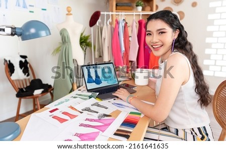 Beautiful asian Fashion designer drawing sketches for new collection on computer laptop. Designer creative workshop studio.