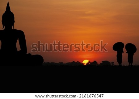 Silhouette with monks and black buddha on sunset background.