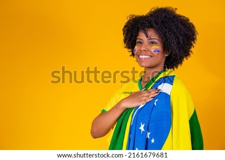 Brazilian fan. wearing Brazilian flag in a portrait, Brazilian fan celebrating football or soccer game on yellow background. Colors of Brazil.World Cup Royalty-Free Stock Photo #2161679681