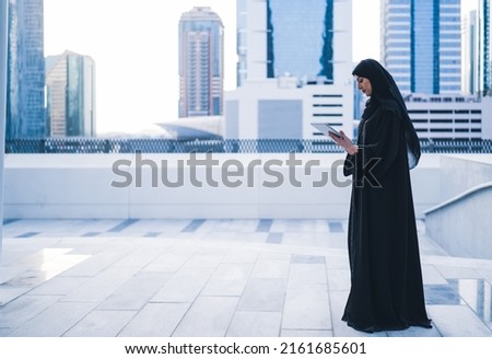 Arab muslim business woman working on tablet in outdoor meeting. Arabian Saudi or Emirati lady businesswoman wearing Abaya  Royalty-Free Stock Photo #2161685601