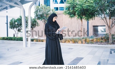 Arab muslim business woman working on tablet in outdoor meeting. Arabian Saudi or Emirati lady businesswoman wearing Abaya  Royalty-Free Stock Photo #2161685603
