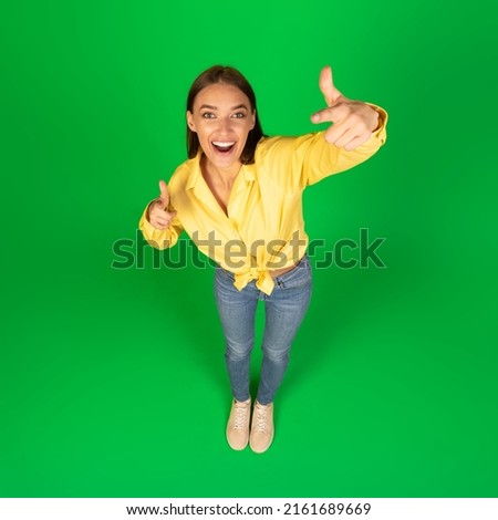 Hey, You. Top view portrait of funny excited young woman pointing fingers at camera posing standing in studio on greeb background. I choose you concept, advertisement banner with cheerful casual lady Royalty-Free Stock Photo #2161689669