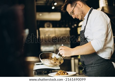 Man chef cooking asian chicken at a cafe kitchen Royalty-Free Stock Photo #2161690099