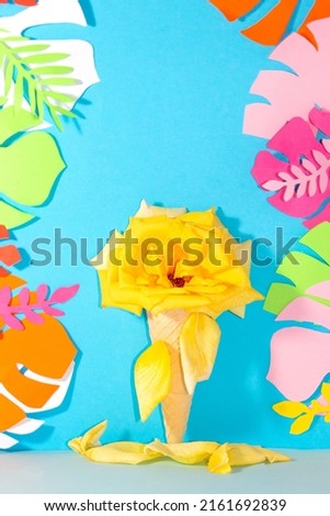 ice cream cone with yellow rose flower that melts and merges on a blue background with colorful jungle leaves, creative tropical design