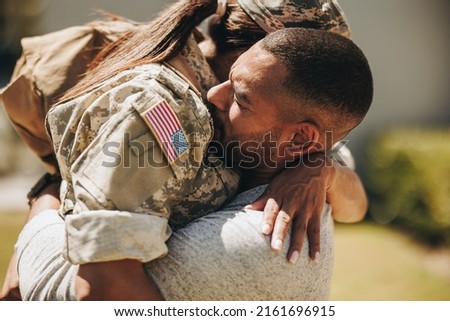Heartwarming military homecoming. Female soldier embracing her husband after returning home from the army. American servicewoman reuniting with her husband after serving her country in the military. Royalty-Free Stock Photo #2161696915