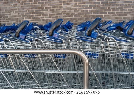 Empty stainless steel modern shopping carts standing at the supermarket in a row in line unused