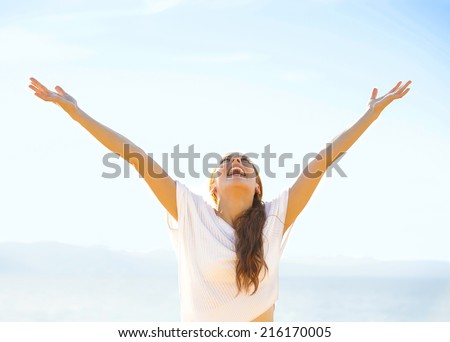 Woman smiling arms raised up to blue sky, celebrating freedom. Positive human emotions, face expression feeling life perception success, peace of mind concept. Free Happy girl on beach enjoying nature Royalty-Free Stock Photo #216170005
