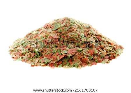 Granular food for aquarium fish isolated on white background. Pile of flakes for feeding tropical aquarium fish. Fish food in flakes. Food for fish in an aquarium isolated on a white background.