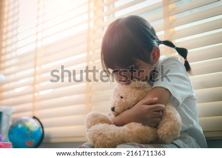 Close up lonely little girl hugging toy, sitting at home alone, upset unhappy child waiting for parents, thinking about problems, bad relationship in family, psychological trauma Royalty-Free Stock Photo #2161711363