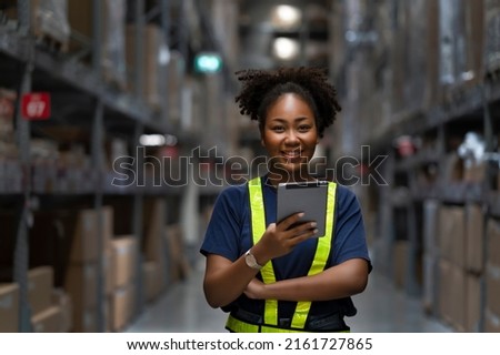Young smart African American woman working in warehouse using the tablet for stock checking and inspection the boxes, logistic warehouse to deliver the shipment, happiness worker with smiling face Royalty-Free Stock Photo #2161727865