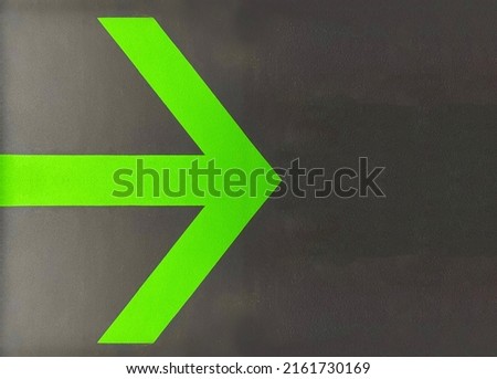 direction arrow on a black wall, green direction arrow on a black background for orientation on a concrete uneven wall, convenient for searching and evacuating people in case of fire, special sign Royalty-Free Stock Photo #2161730169