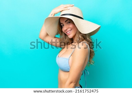 Young caucasian woman isolated on blue background happy in swimsuit in summer holidays