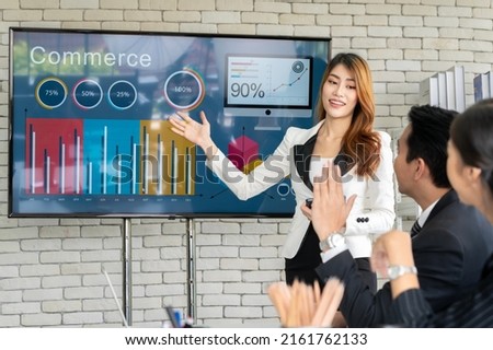 An Asian businessman is presenting his company performance report to his boss or group of male and female colleagues with confidence and professionalism.