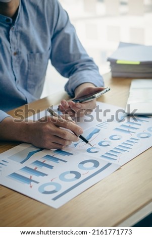 financial concept close-up businessman holding a graph pen press a calculator And make money by writing reports, memos and analyzing vertical image business documents.