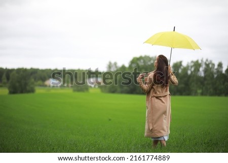 Young girl in a green park in rainy weather
