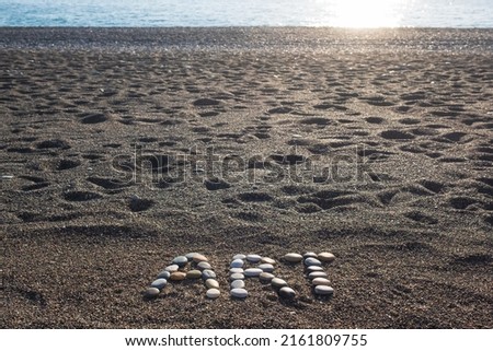 Word art made from stones on sandy beach during sunset