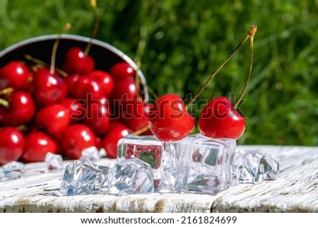Cherries and ice on a wooden background in a summer garden.Close-up.

