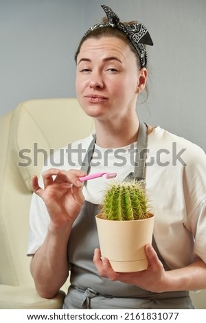 a cheerful young woman holds a prickly cactus in her hands and brings a pink razor to it. depilation