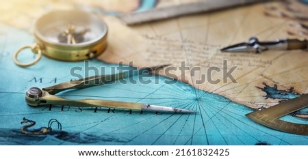 An old geographic map with navigational tools: compass, divider, ruler, protractor. View of the workplace of ship's captain. Travel, geography, navigation, tourism and exploration concept background. Royalty-Free Stock Photo #2161832425