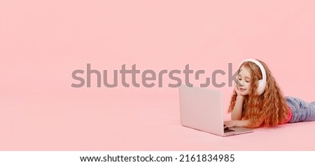 banner of adorable child girl is sitting in the twine next to a laptop. kid in white headphones stretching and learns homework or watching cartoons, listening music.