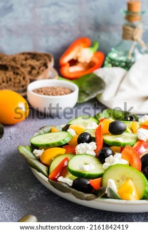 Greek salad of fresh vegetables, leaves and feta cheese on a plate on the table. Mediterranean homemade dish. Vertical view. Close-up