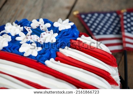 Closeup of a patriotic American flag cake on wooden background with mini flags. Memorial day, 4th of July, Independence Day, Flag Day theme.
