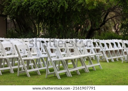 White resin folding chairs with padding arranged for an outdoor wedding ceremony. Royalty-Free Stock Photo #2161907791