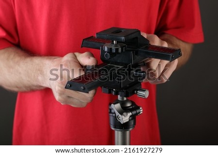 the young man takes off the slider from the tripod on a gray background
